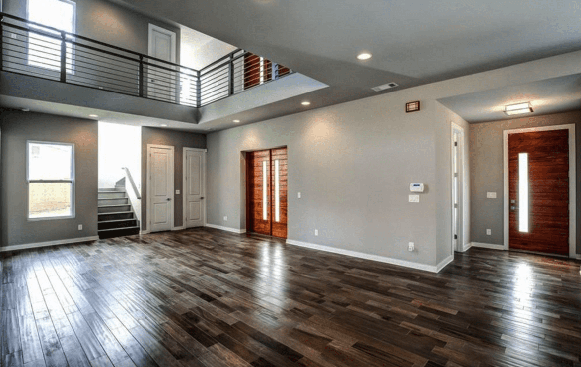 An empty living room with hardwood floors and stairs.
