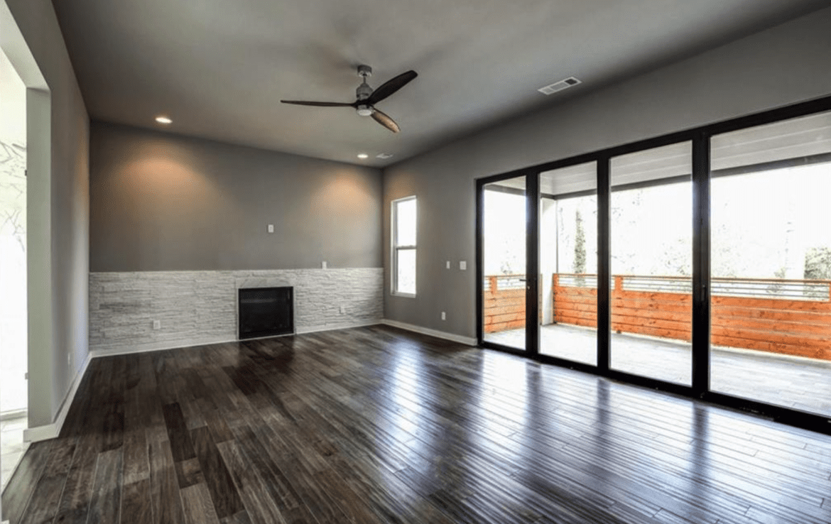 Empty living room with hardwood floors and a ceiling fan.