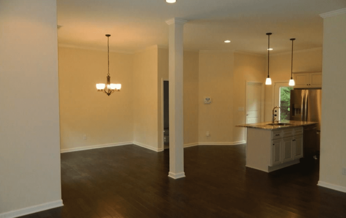 An empty kitchen with hardwood floors and a fireplace.