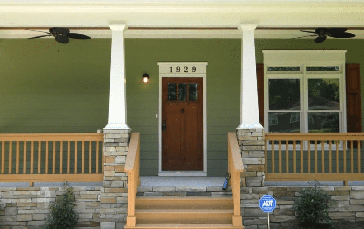 The front porch of a home is green and has wooden steps.