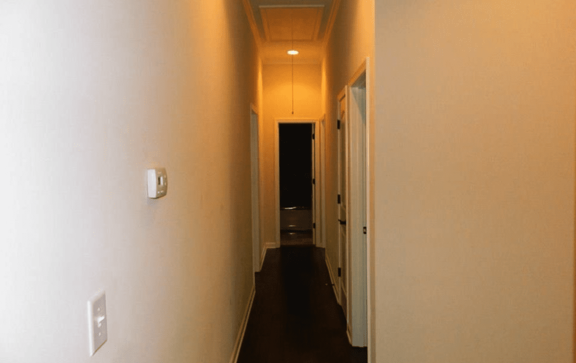 A hallway with white walls and a wooden floor.