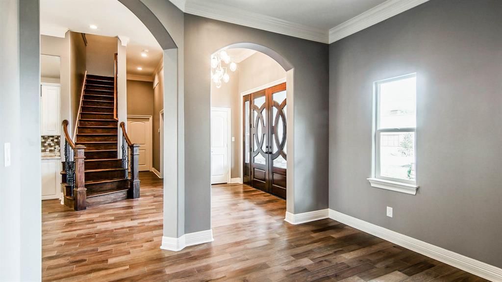 A hallway in a home with hardwood floors and a staircase.