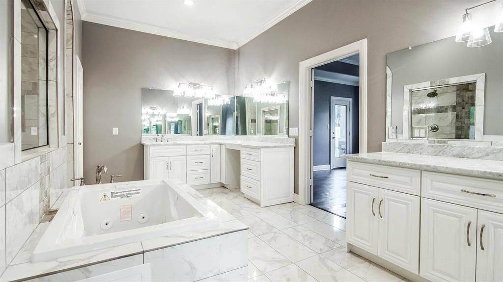 A bathroom with white cabinets and marble counter tops.