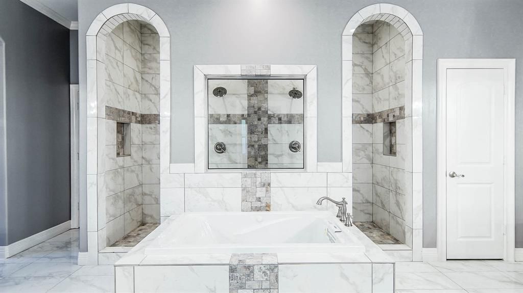 A bathroom with a large tub and marble walls.