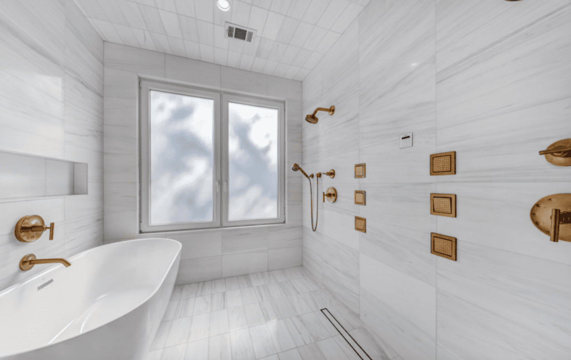 A white bathroom with gold fixtures and a tub.