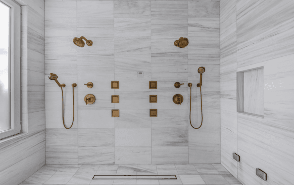 An image of a bathroom with a shower and two faucets.