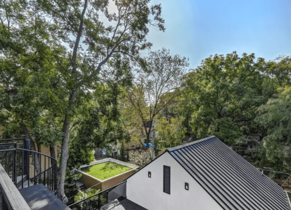 A rooftop deck with a pool and trees.