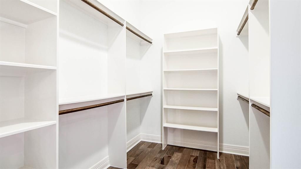 A white closet with shelves and a wooden floor.