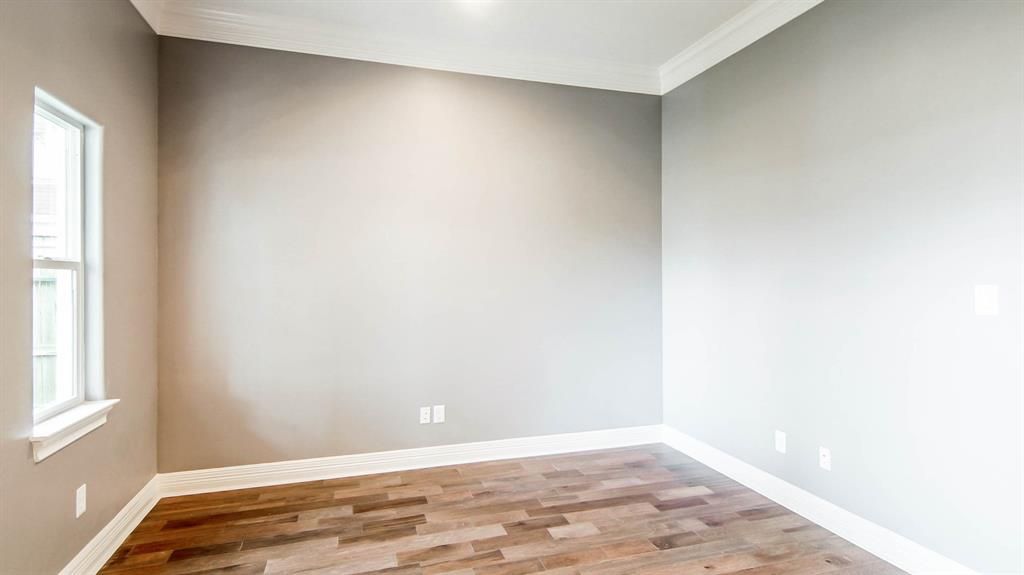 An empty room with gray walls and wood floors.