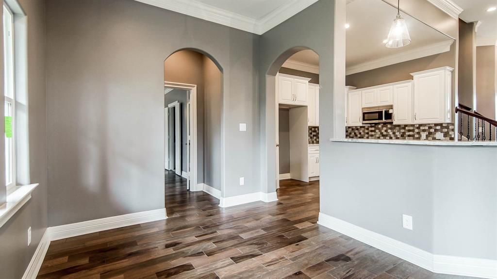 A hallway in a home with gray walls and hardwood floors.