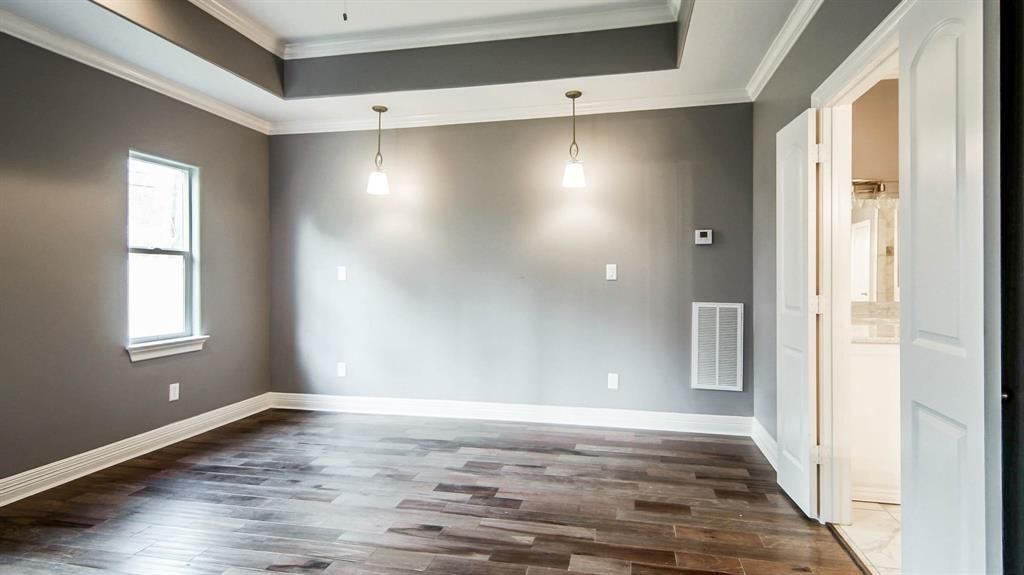 An empty room with gray walls and hardwood floors.