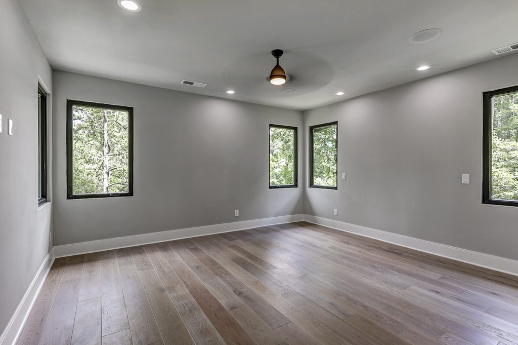 An empty room with gray walls and hardwood floors.