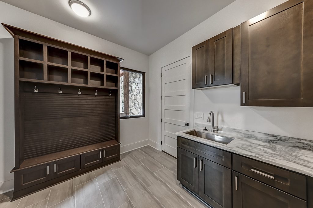 A laundry room with a sink and cabinets.