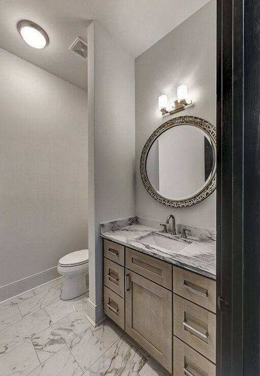 A bathroom with marble counter tops and a mirror.