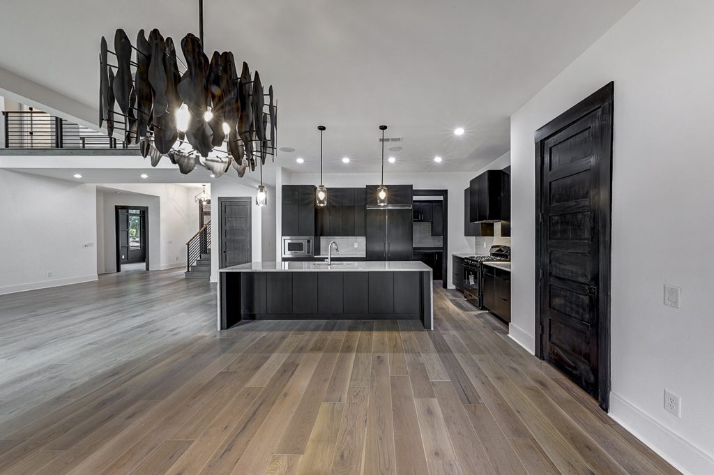 A modern kitchen with black cabinets and hardwood floors.