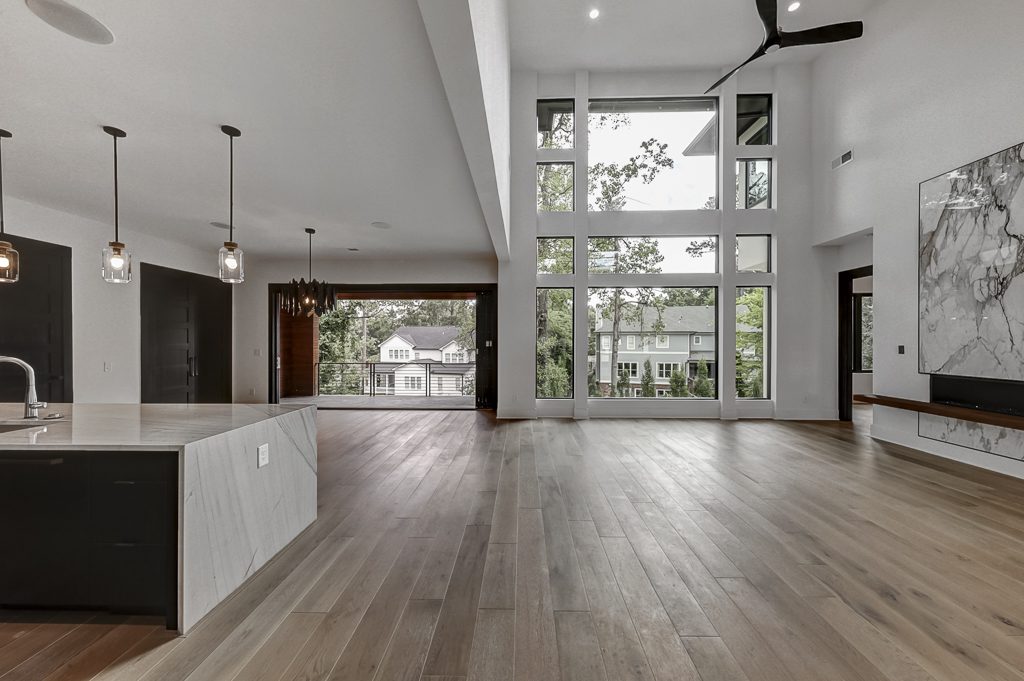 A modern kitchen with hardwood floors and large windows.