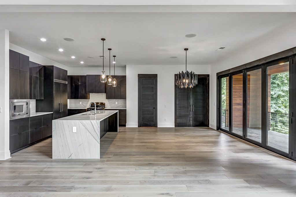 A modern kitchen with wood floors and black cabinets.