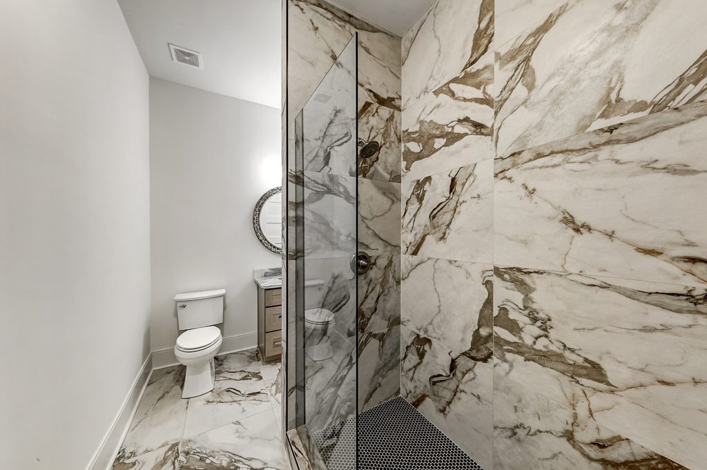 A marble bathroom with a toilet and shower.