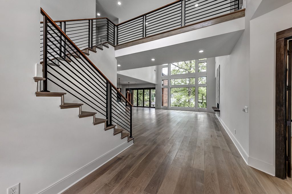 A modern staircase in a home with wood floors and metal railings.