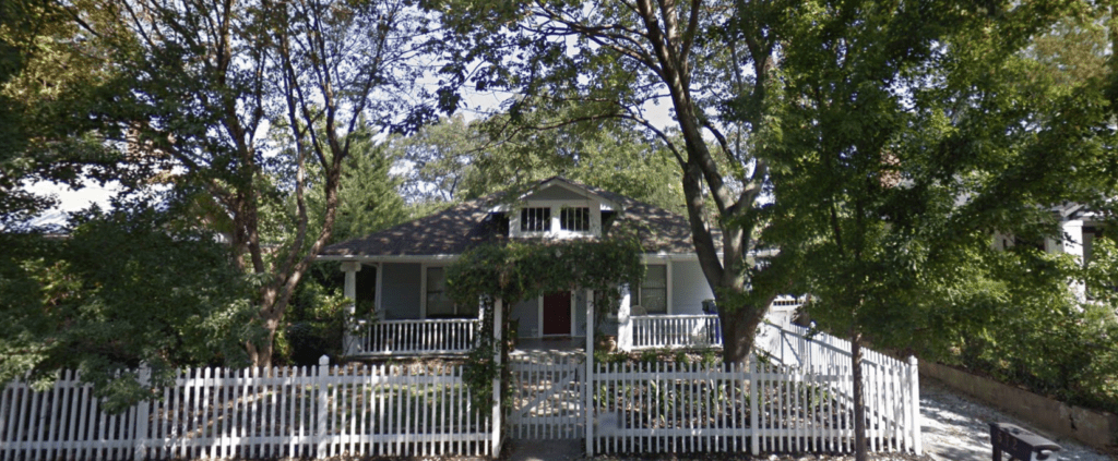 A google street view of a house with a white picket fence.